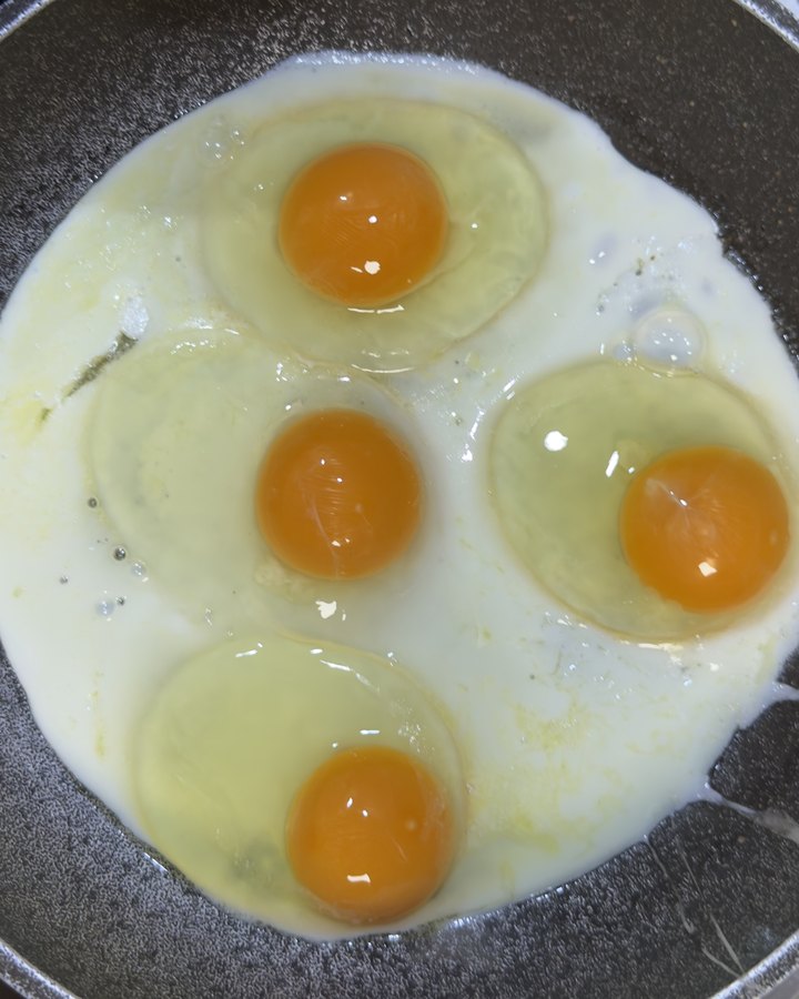 Cuatro huevos Huevos Felices friéndose, con la yema naranja intensa